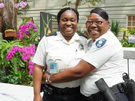 Two OPS Officers in uniform embrace and smile for the camera. 